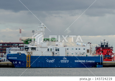 Groenewind offshore wind service operation vessel moored at a harbor pier under a cloudy sky 143724219