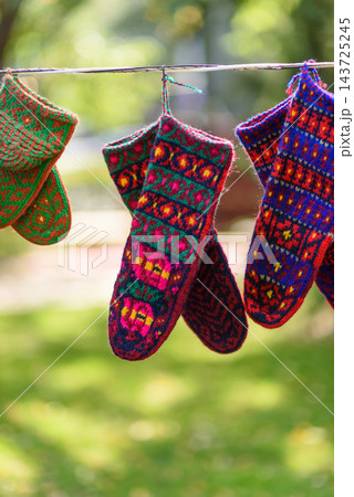 Three pairs of hand-knitted socks hanging on a white clothesline in a natural outdoor setting Three pairs of hand-knitted socks hanging on a white clothesline in a natural outdoor setting 143725245