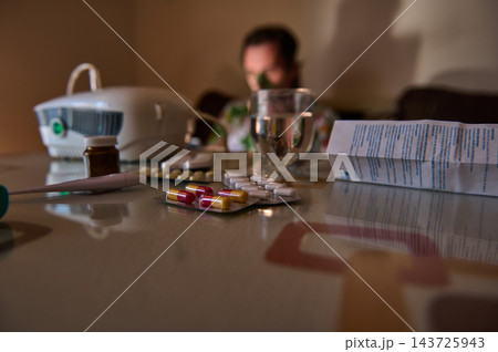 Sick woman at home with medication, pills and nebulizer on table Sick woman at home with medication, pills and nebulizer on table 143725943