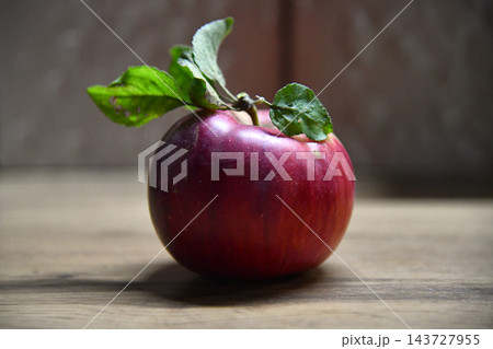 Ripe red apple close-up with sun rays and apple orchard in the 143727955