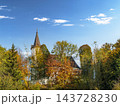 Historic Church Tower Peeking Through Autumn Trees Under A Bright Blue Sky In Rural Landscape 143728230