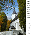White Church With Steeple Surrounded by Autumn Trees and Blue Sky in Peaceful Setting 143728233