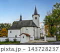 Historic White Church With Steeple and Walled Courtyard Surrounded by Autumn Trees at Dusk 143728237