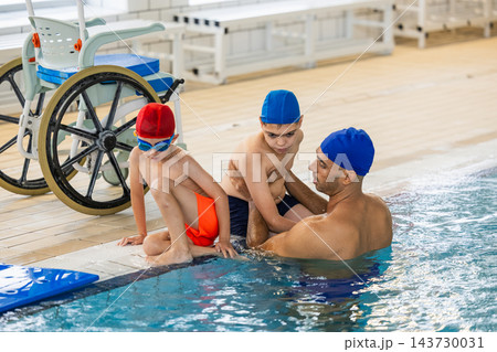 Instructor assisting children with disabilities in pool Instructor assisting children with disabilities in pool 143730031