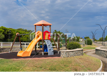 Empty children's playground with yellow slide in seaside park 143730174