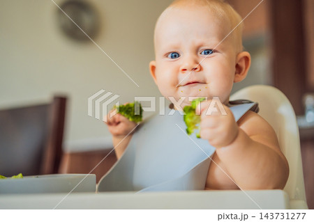 Baby reacting to the taste of broccoli during complementary feeding. 143731277