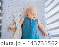 Sleeping infant with a fabric rabbit on soft nursery bedding. 143731562