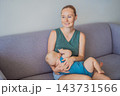 Mother feeding her infant at the breast on a living room sofa. 143731566