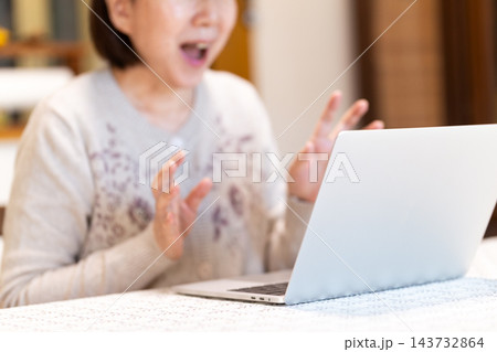 家のリビングでパソコンを見て驚くミドル・シニア女性 143732864