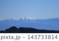 青くかすむ山並みの奥に連なる、雪をかぶった冬の連峰と青空 143733814