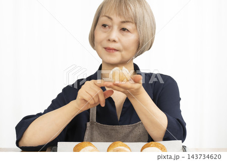手作りパンを楽しむシニア女性 手作りパンを楽しむシニア女性 143734620