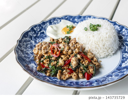 pad kaprow gai spicy chicken and basil stir-fry Thai food meal on modern phuket restaurant table 143735729