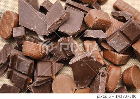 Assorted chocolate pieces scattered on a woven surface Assorted chocolate pieces scattered on a woven surface 143737580