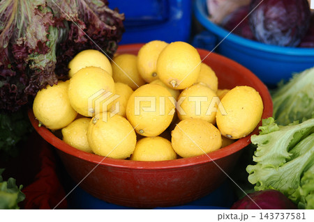 Bowl of lemons displayed with leafy greens at an outdoor market stall Bowl of lemons displayed with leafy greens at an outdoor market stall 143737581