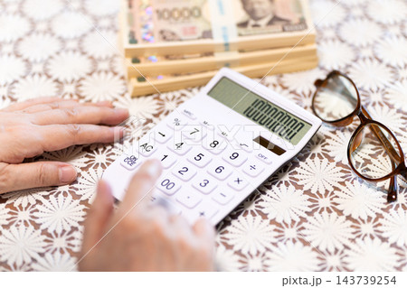 電卓でお金を計算するミドル・シニア女性の手元 143739254