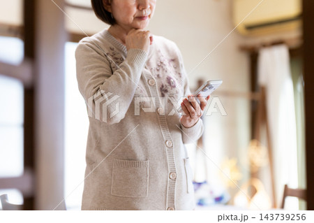 家でスマホを見るミドル・シニア女性 143739256