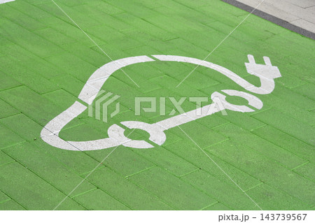 A white electric vehicle symbol on a green parking spot surface A white electric vehicle symbol on a green parking spot surface 143739567
