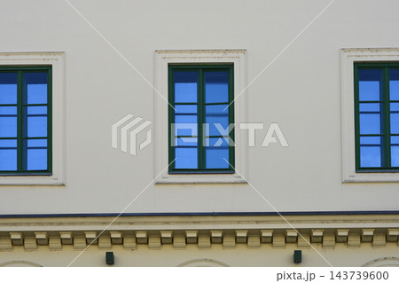 A row of green windows on a minimalistic beige facade A row of green windows on a minimalistic beige facade 143739600