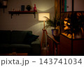 Cozy green sofa under warm lamp stylist staged hygge corner with wood paneling, floating shelf, potted plant, soft cushions, ambient lighting creating intimate mood Cozy green sofa under warm lamp stylist staged hygge corner with wood paneling, floating shelf, potted plant, soft cushions, ambient lighting creating intimate mood 143741034