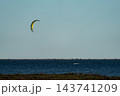 Lonely kitesurfer gliding across wide open sea horizon 143741209