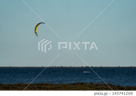 Lonely kitesurfer gliding across wide open sea horizon 143741209