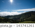 渋峠から望む青空と輝く太陽の下に広がる芳ヶ平の壮大な山並みと雲 143741261