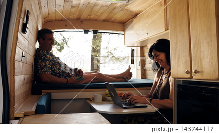 Mature couple enjoying van life working remotely 143744117