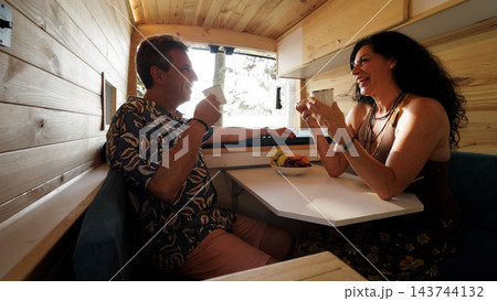 Mature couple enjoying coffee together in camper van 143744132
