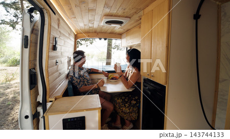 Mature couple enjoying breakfast inside camper van 143744133