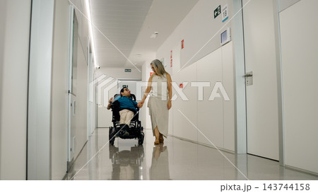 Woman holding hand of man in wheelchair at hospital Woman holding hand of man in wheelchair at hospital 143744158