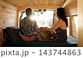 Mature couple relaxing inside camper van enjoying sunset view 143744863