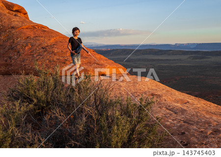 Boy Hiking at Sunset on Devils Garden Trail, Utah 143745403