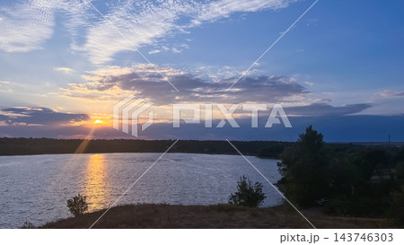 Sunset over a lake with golden reflections and silhouetted trees 143746303