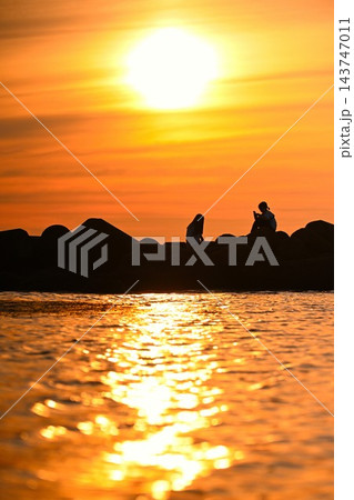夕日に照らされた海岸と人物のシルエット(新潟県新潟市) 夕日に照らされた海岸と人物のシルエット(新潟県新潟市) 143747011