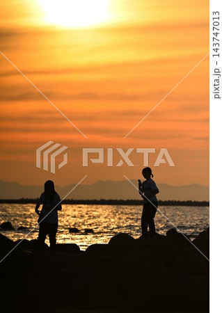 夕日に照らされた海岸と人物のシルエット(新潟県新潟市) 夕日に照らされた海岸と人物のシルエット(新潟県新潟市) 143747013
