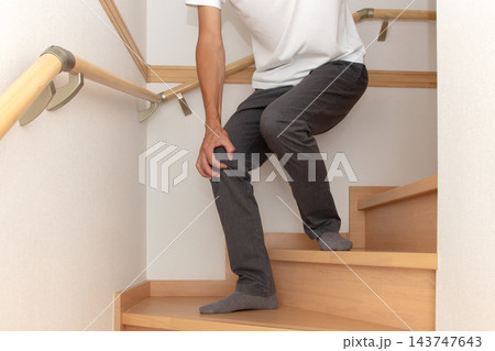 階段の途中で手すりにつかまり膝に手を当て痛がる人 143747643