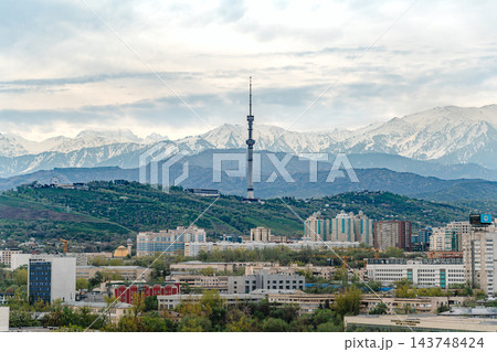 Almaty city skyline with snow capped mountains, red and white TV tower and green spring trees Almaty city skyline with snow capped mountains, red and white TV tower and green spring trees 143748424