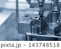 The hole deburring process on metal casting parts using a chamfer tool in a blue tone scene 143748518