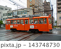 街中を走るオレンジ色の路面電車 143748730