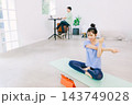 リビングでヨガをする妻とその奥で仕事をする夫 143749028