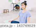 リビングでヨガをする妻とその奥で仕事をする夫 143749029
