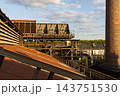 High angle telephoto landscape of historic industrial heat exchanger cooling plant with rusty corrugated roof tall brick smokestack chimney and blue sky in Duisburg Ruhr region Westphalia Germany 143751530