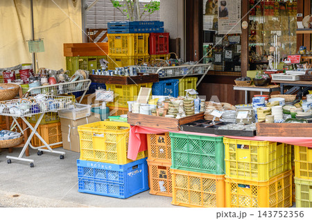 店先に茶碗や湯呑み、小皿などの陶器がずらりと並び色鮮やかなプラスチックケースが積まれた和雑貨店の風景 店先に茶碗や湯呑み、小皿などの陶器がずらりと並び色鮮やかなプラスチックケースが積まれた和雑貨店の風景 143752356