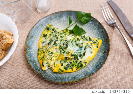 Omelet with spinach, decorated with sprig of parsley, slices of bran bread Omelet with spinach, decorated with sprig of parsley, slices of bran bread 143754339
