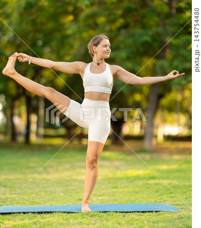 Sporty girl performing yoga asanas on green meadow in summer 143754480