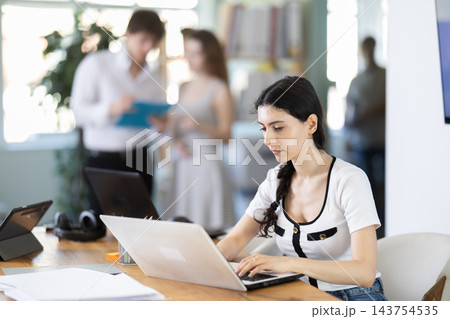 Girl sitting at desk is working on laptop computer. Girl sitting at desk is working on laptop computer. 143754535