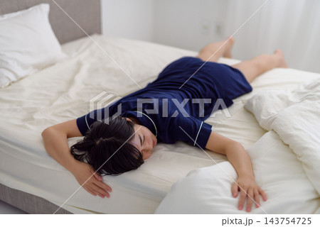 ベッドでうつ伏せに倒れ込む若い女性 ベッドでうつ伏せに倒れ込む若い女性 143754725