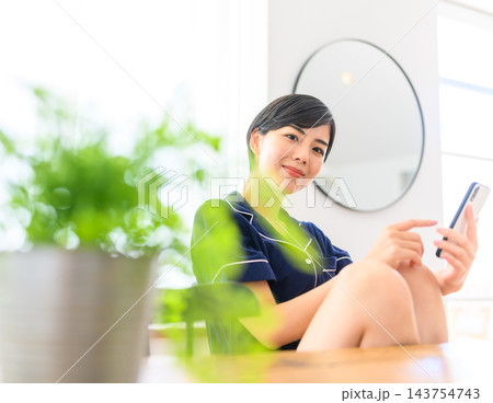 スマホを操作し微笑む女性 スマホを操作し微笑む女性 143754743