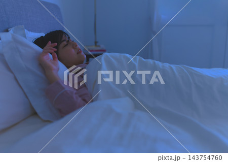 夜の寝室でベッドに横たわり眠る女性 夜の寝室でベッドに横たわり眠る女性 143754760