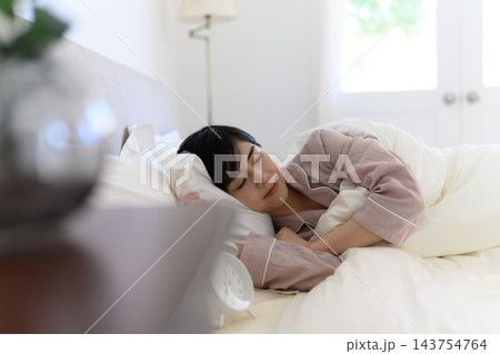 目覚まし時計と眠る女性 143754764